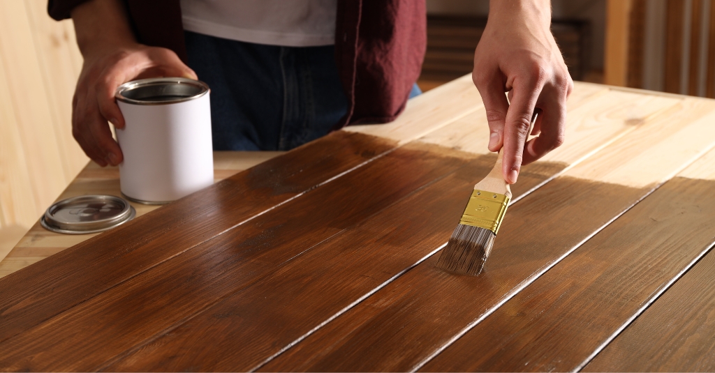 man varnishing wood table